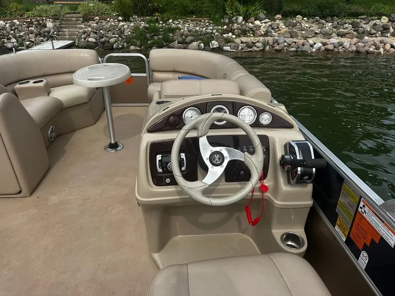 Slide: The Image of The image shows the cockpit of a 2013 Xcursion 23RF pontoon boat with beige seating. - 7