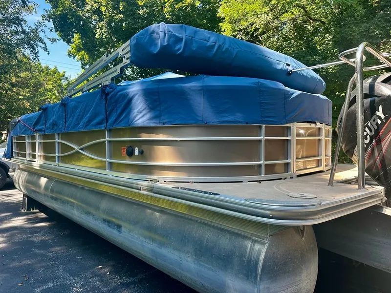 Slide: The Image of A 2013 Xcursion 23RF pontoon boat with a blue cover, parked on a trailer. - 18