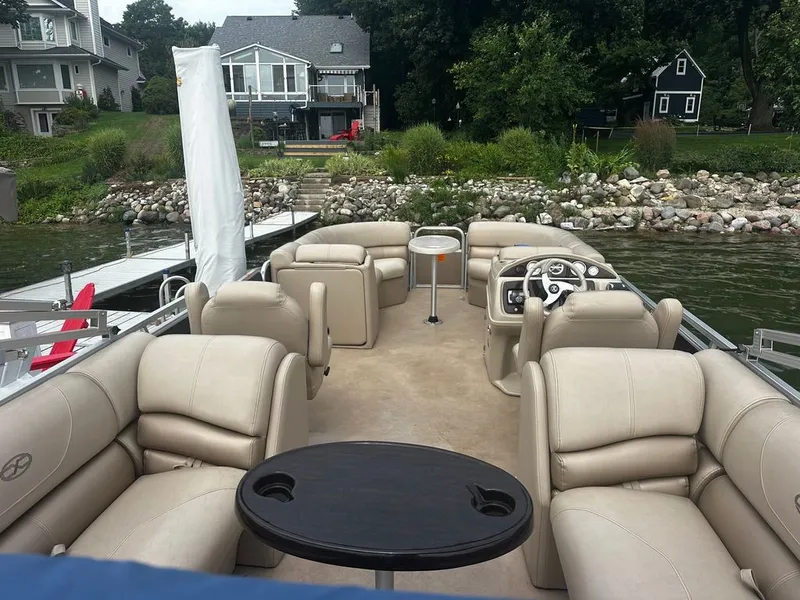 Slide: The Image of A pontoon boat with beige leather seating and a small table, docked by a calm lake. - 4