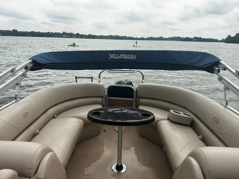 Slide: The Image of The image shows the interior of an Xcursion 23RF pontoon boat with beige seating and a table. - 11