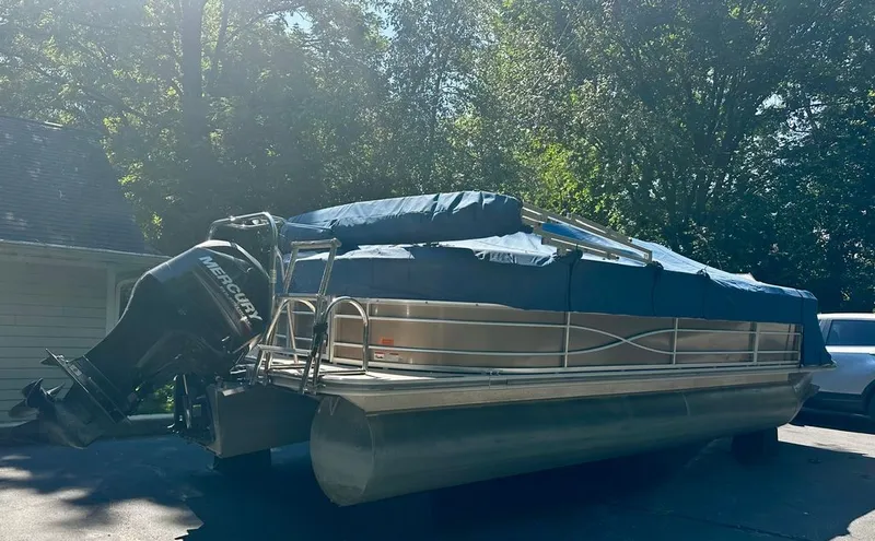 Slide: The Image of A 2013 Xcursion 23RF pontoon boat with a Mercury outboard motor, covered and on a trailer. - 1