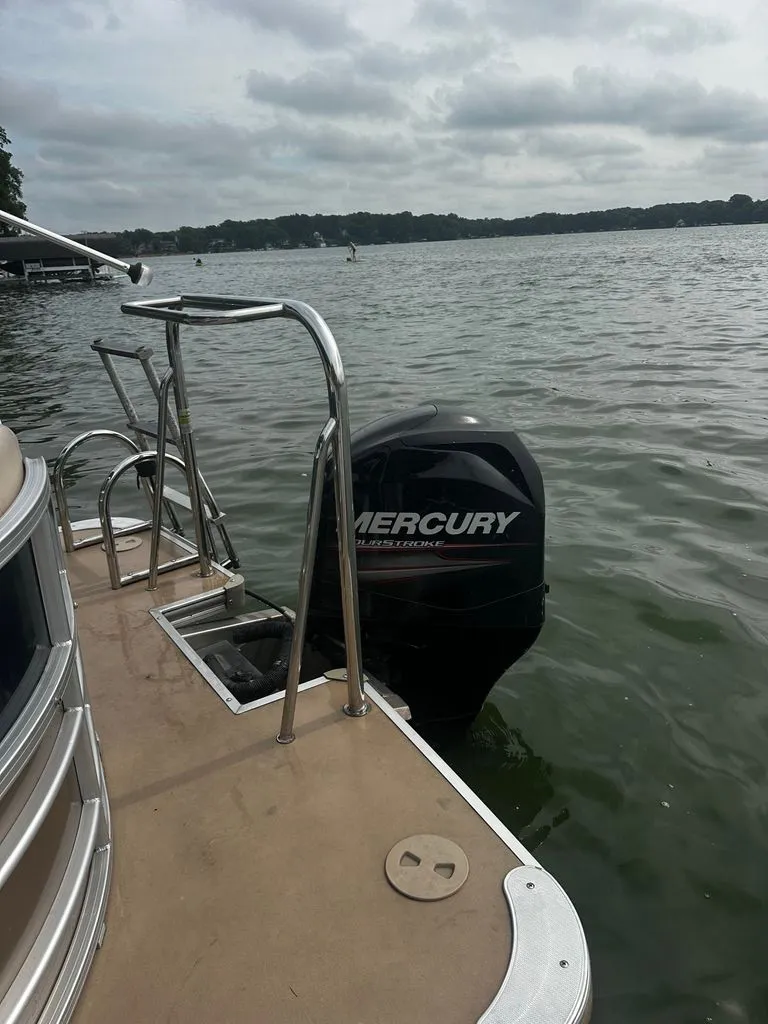 Slide: The Image of A 2013 Xcursion 23RF pontoon boat with a Mercury outboard motor, floating on a calm lake. - 13