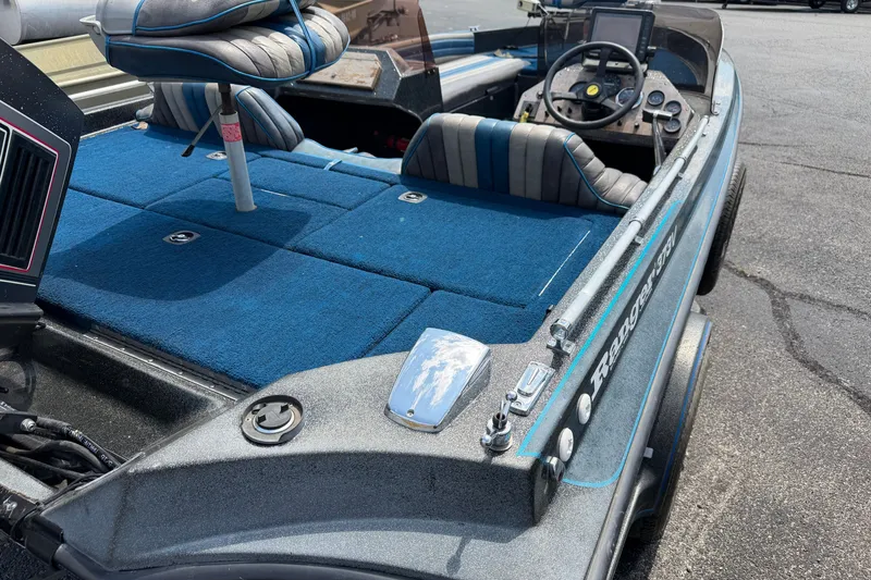 Slide: The Image of 1989 Ranger 373V boat interior with blue carpet and striped seats, showcasing steering console. - 1