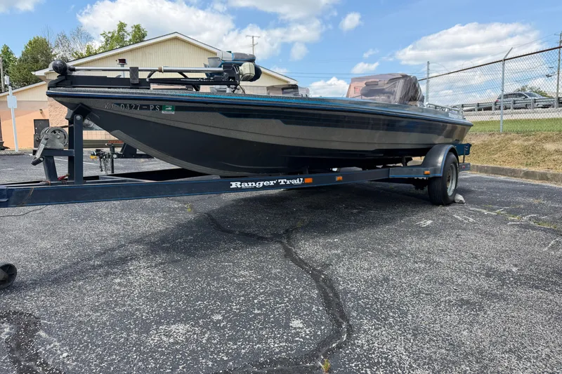 The Image of 1989 Ranger 373V boat on trailer in parking lot, under blue sky. - 0