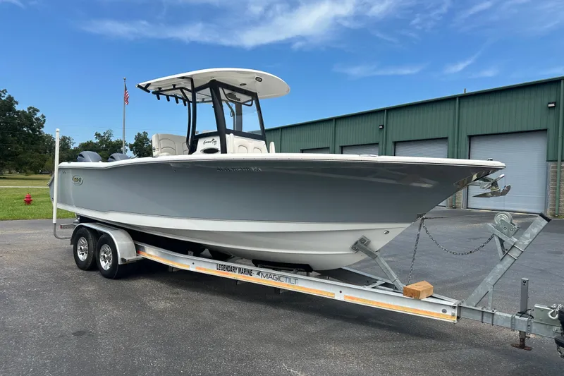 The Image of 2019 Sea Hunt Gamefish 27CB boat on trailer, parked outside a green building. - 0