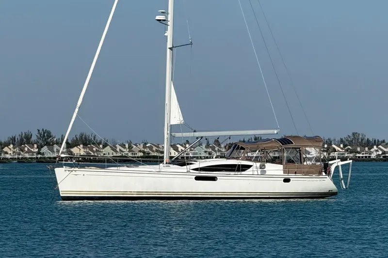 The Image of 2011 Jeanneau Sun Odyssey 50 DS sailboat on calm water, with coastal houses in the background. - 0