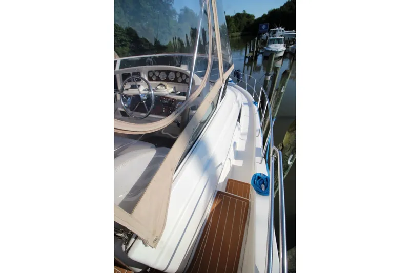 Slide: The Image of 2004 Silverton 410 Sport Bridge yacht with helm, docked in a serene marina setting. - 20