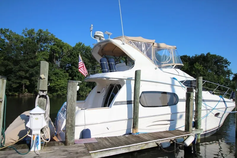 Slide: The Image of 2004 Silverton 410 Sport Bridge yacht docked by a serene waterfront. - 7