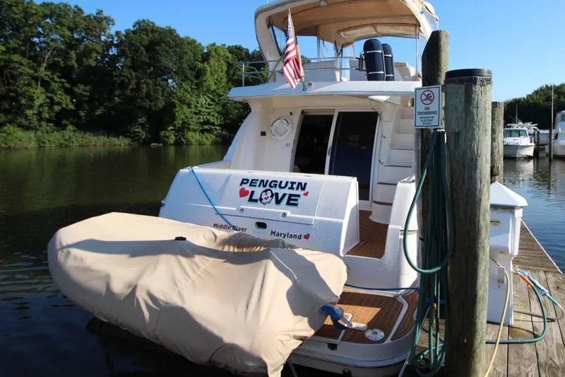 Slide: The Image of 2004 Silverton 410 Sport Bridge yacht docked, featuring "Penguin Love" name and Maryland location. - 6