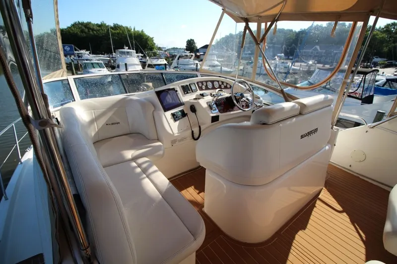 Slide: The Image of 2004 Silverton 410 Sport Bridge yacht interior with helm, white seating, and marina view. - 13