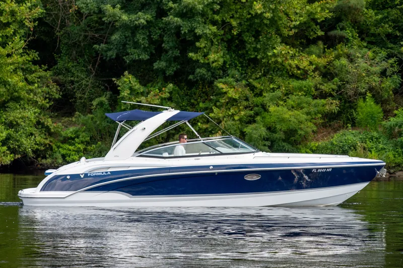 Slide: The Image of 2008 Formula 310 Bowrider boat cruising on a calm lake with lush green trees. - 1
