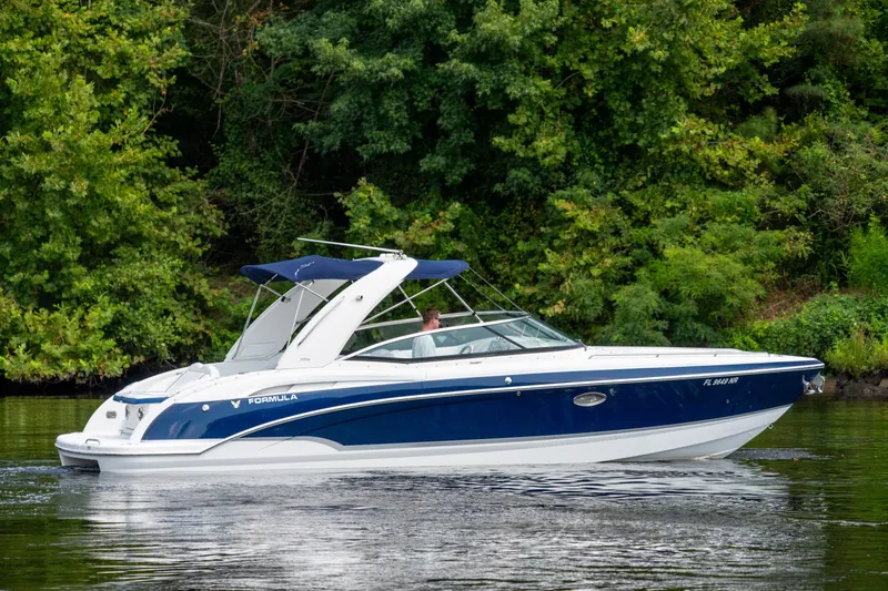 Slide: The Image of 2008 Formula 310 Bowrider cruising on a serene lake with lush green trees. - 2