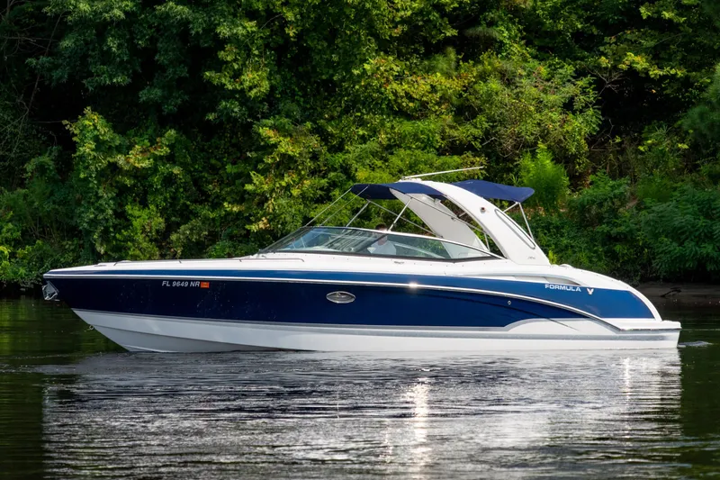 Slide: The Image of 2008 Formula 310 Bowrider boat cruising on a calm lake with lush green trees. - 8