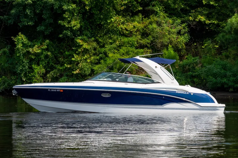 Slide: The Image of 2008 Formula 310 Bowrider boat cruising on a calm lake with lush green trees. - 7