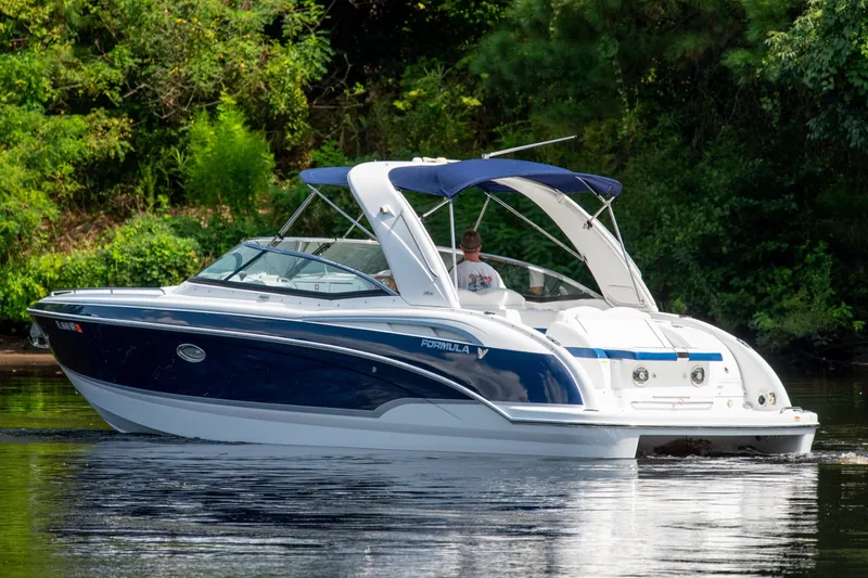 Slide: The Image of 2008 Formula 310 Bowrider cruising on a calm river with lush greenery. - 6
