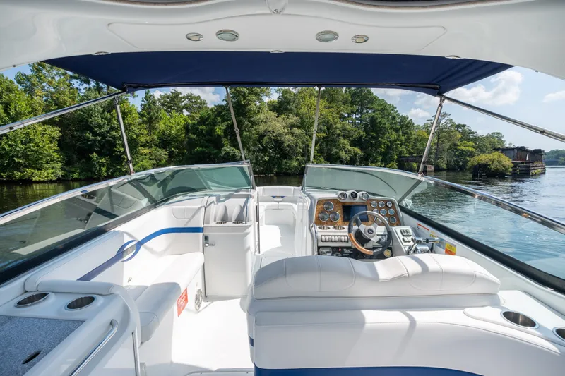Slide: The Image of 2008 Formula 310 Bowrider boat interior with steering wheel and seating, on a scenic river. - 26