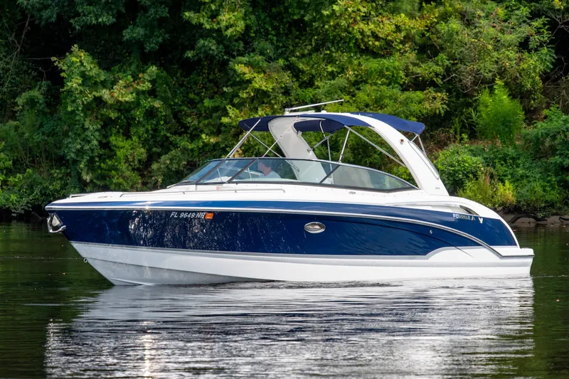 Slide: The Image of 2008 Formula 310 Bowrider boat cruising on a calm river with lush green background. - 9