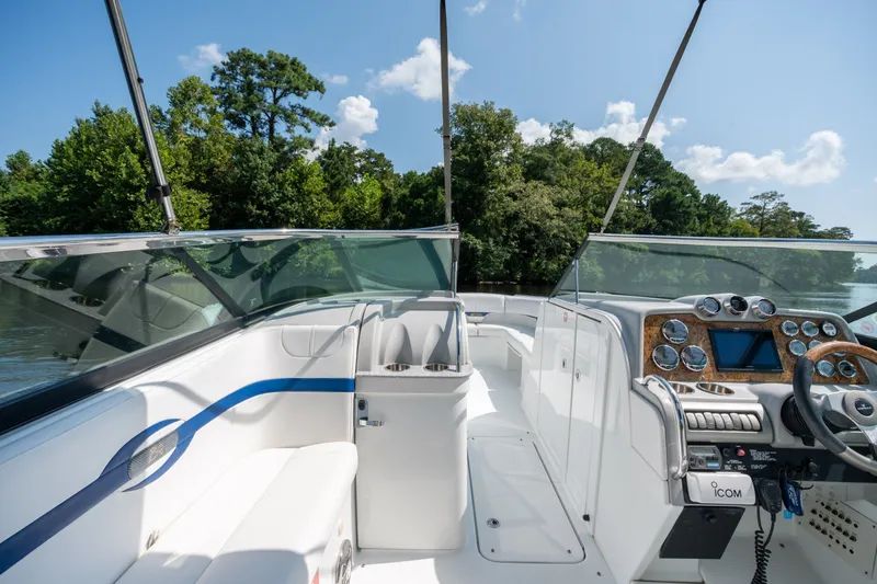 Slide: The Image of 2008 Formula 310 Bowrider boat interior with sleek dashboard and seating, surrounded by lush greenery. - 20