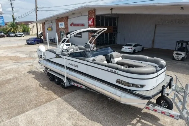 The Image of 2024 Avalon Catalina Platinum Quad Lounge boat on trailer outside dealership. - 0