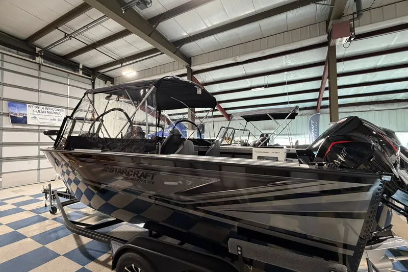 Slide: The Image of 2027 Starcraft Fishmaster 210 boat displayed indoors with sleek design and powerful engine. - 1