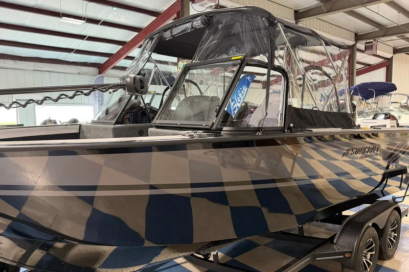 Slide: The Image of 2027 Starcraft Fishmaster 210 boat in showroom, featuring sleek design and protective canopy. - 2