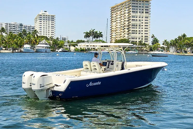 Slide: The Image of 2014 Sailfish 320 CC boat cruising in a sunny waterfront cityscape. - 30