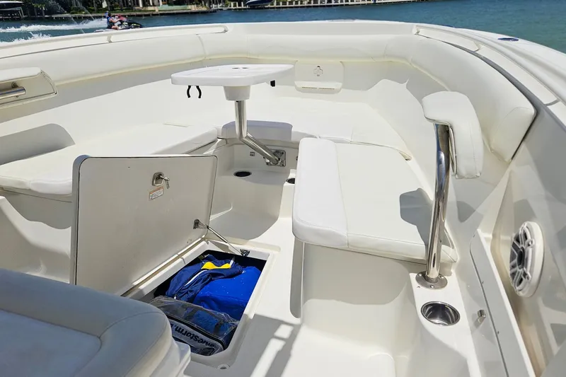 Slide: The Image of 2014 Sailfish 320 CC boat interior with seating, storage, and table on a sunny day. - 23