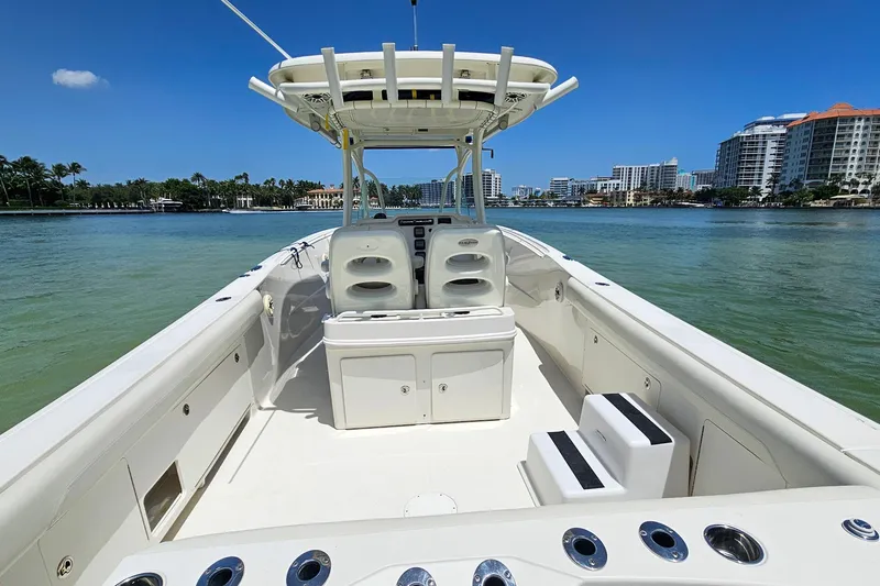 Slide: The Image of 2014 Sailfish 320 CC boat interior with seating, on calm water, cityscape in background. - 14