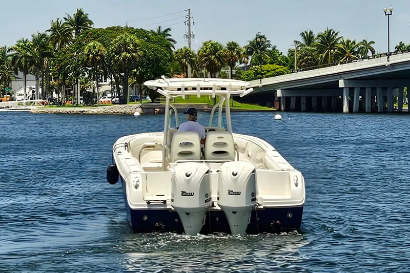 Slide: The Image of 2014 Sailfish 320 CC boat cruising on a sunny waterway near a bridge and palm trees. - 28