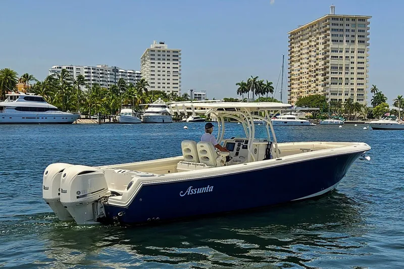 Slide: The Image of 2014 Sailfish 320 CC boat cruising in a marina with cityscape background. - 27