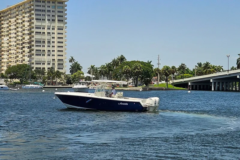 Slide: The Image of 2014 Sailfish 320 CC boat cruising near a waterfront cityscape with a bridge and palm trees. - 29