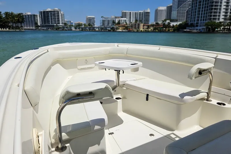 Slide: The Image of 2014 Sailfish 320 CC boat interior with seating and table, overlooking waterfront cityscape. - 22