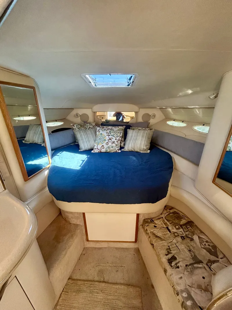 Slide: The Image of The cabin of the 1999 Sea Ray 340 Sundancer features a cozy bed with a blue cover and pillows. - 17