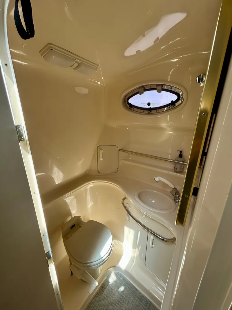 Slide: The Image of The image shows a compact boat bathroom with a toilet, sink, and porthole. - 22