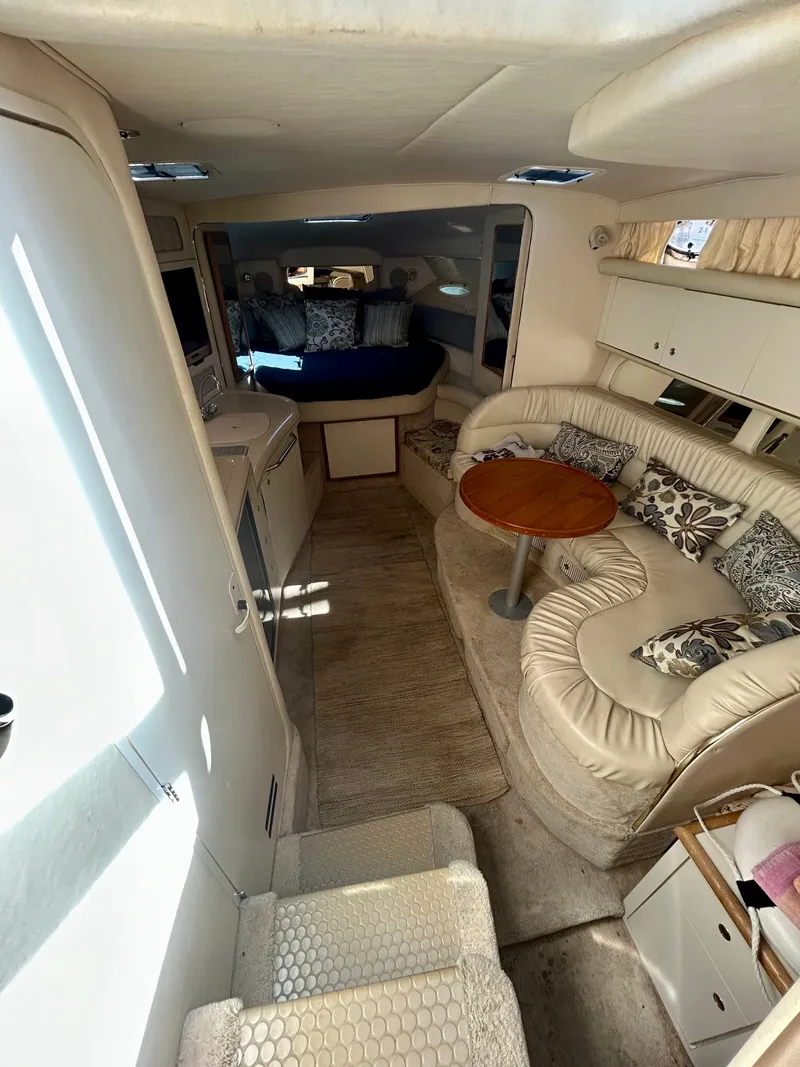 Slide: The Image of Interior of a 1999 Sea Ray 340 Sundancer with cream upholstery and a round wooden table. - 16