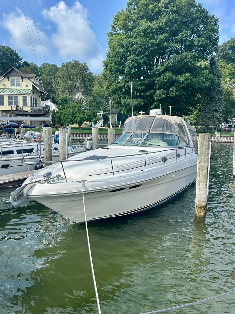 The Image of A 1999 Sea Ray 340 Sundancer docked in a calm area, surrounded by trees. - 0