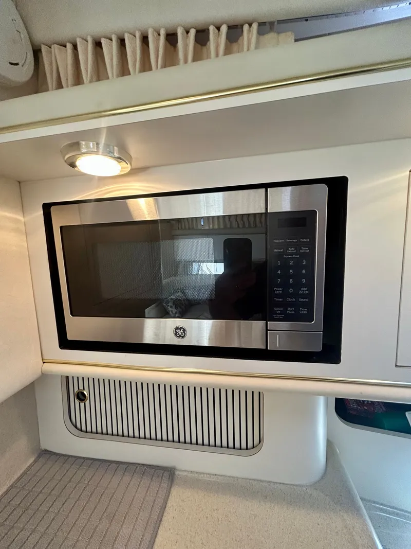Slide: The Image of The galley of a 1999 Sea Ray 340 Sundancer featuring a built-in microwave. - 23