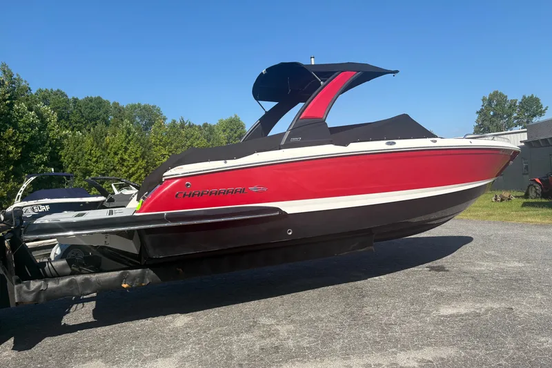 Slide: The Image of 2021 Chaparral 267 SSX boat in vibrant red, parked outdoors on a sunny day. - 2