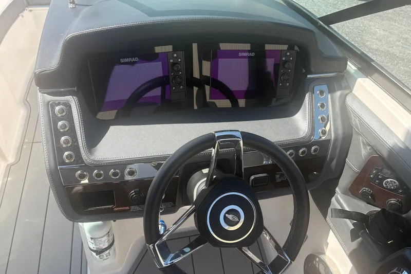 Slide: The Image of 2021 Chaparral 267 SSX boat dashboard with dual Simrad displays and steering wheel. - 10