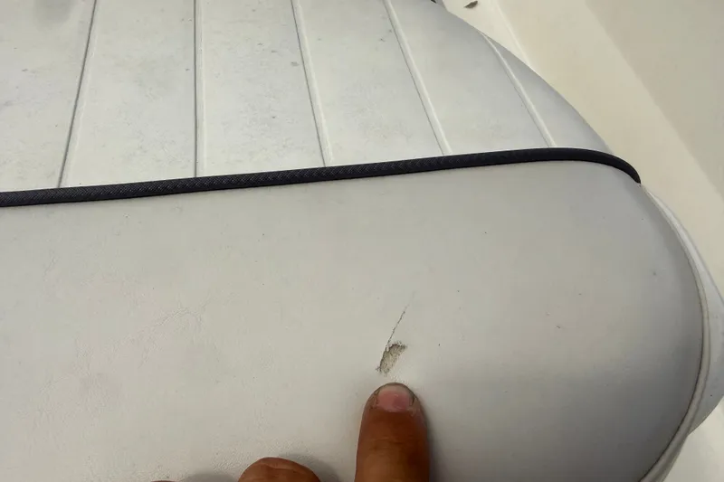 Slide: The Image of 2016 Mako Pro Skiff 16 CC seat with a small tear, highlighted by a pointing finger. - 25