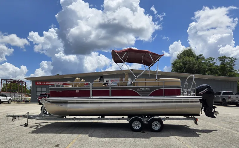 The Image of A 2020 Lowe SF 232 pontoon boat on a trailer, featuring a red canopy, parked in a lot. - 1
