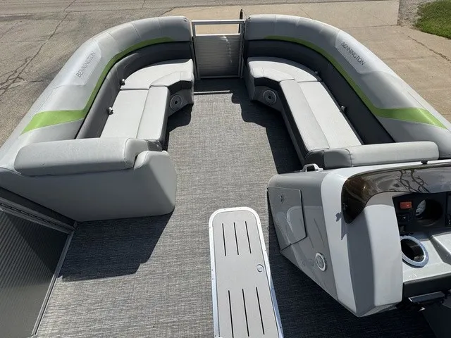 Slide: The Image of The image shows the spacious deck of a Bennington 22 SSBX pontoon boat with gray and green seating. - 7
