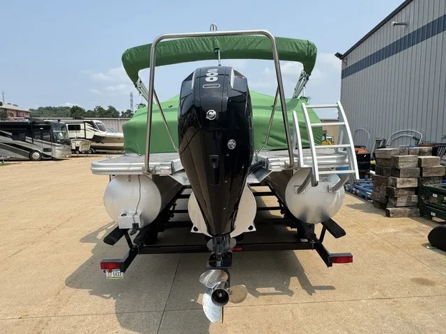 Slide: The Image of A 2022 Bennington 22 SSBX pontoon boat with a green canopy and outboard motor on a trailer. - 4