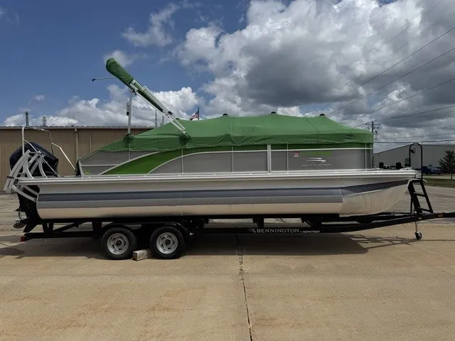 Slide: The Image of A 2022 Bennington 22 SSBX pontoon boat on a trailer, covered with green tarps. - 3