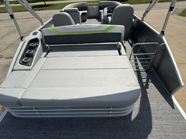 Slide: The Image of The image shows the deck of a Bennington 22 SSBX pontoon boat with gray upholstery and cup holders. - 16