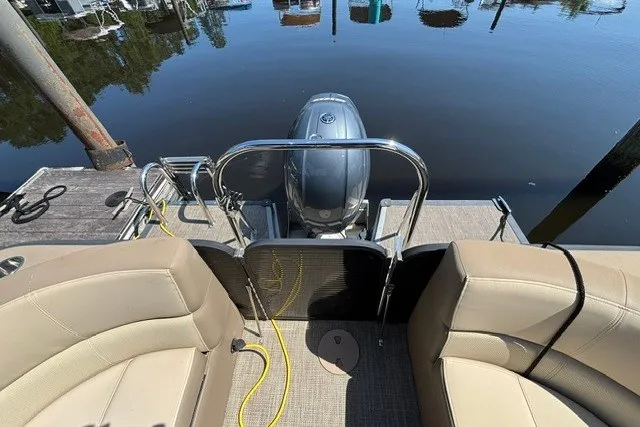 Slide: The Image of 2022 Manitou 23 Aurora pontoon boat with motor, docked on calm water. - 23