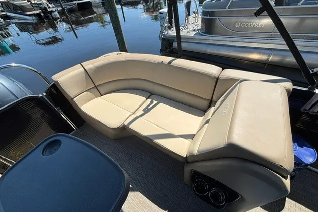Slide: The Image of Luxurious seating on 2022 Manitou 23 Aurora pontoon boat, docked by the water. - 16