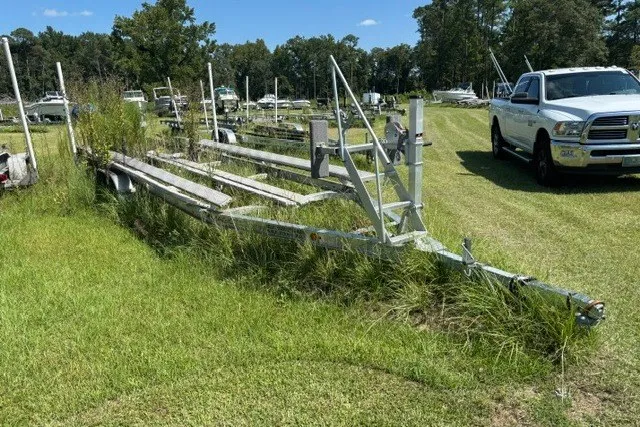 Slide: The Image of Boat trailer on grassy field near parked vehicles, surrounded by trees under a clear sky. - 30