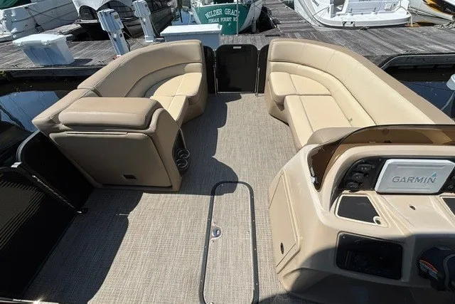 Slide: The Image of 2022 Manitou 23 Aurora pontoon boat interior with beige seating and Garmin navigation system. - 15