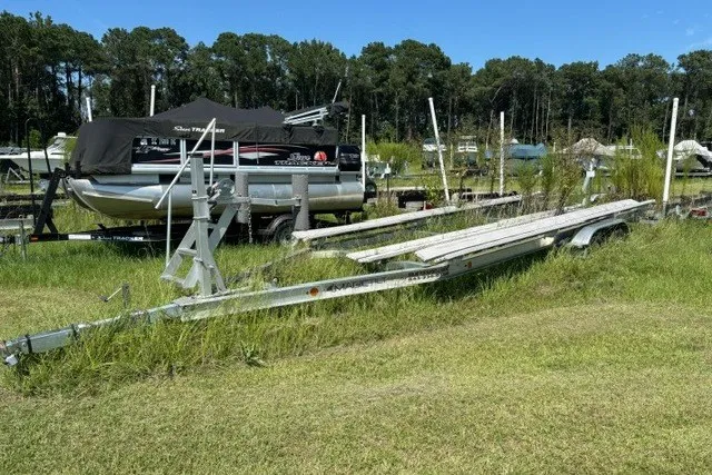 Slide: The Image of 2022 Manitou 23 Aurora pontoon boat on trailer in grassy storage area. - 29